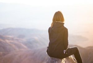 Frau sitzt auf einem Gipfel