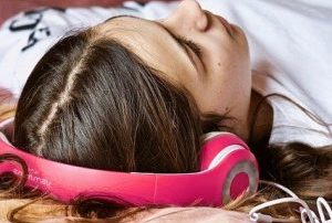 Frau mit Kopfhörern liegt auf einem Bett
