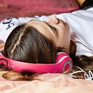 Frau mit Kopfhörern liegt auf einem Bett