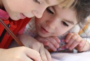 Zwei Kinder schreiben etwas in ein Buch