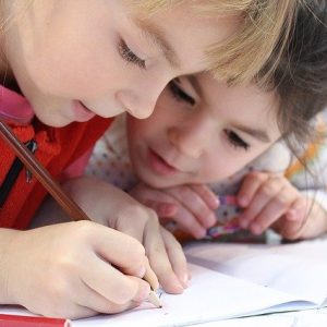 Zwei Kinder schreiben etwas in ein Buch