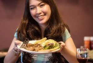 Frau trägt Teller mit Fast Food